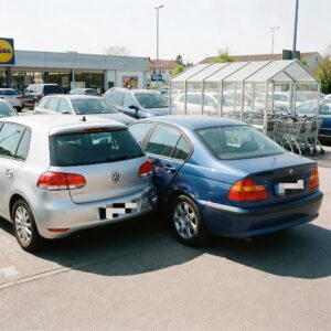 Stoßstange eines rückwärts ausparkenden Autos drückt eine deutliche Delle in die Fahrertür eines vorbeifahrenden Wagens.