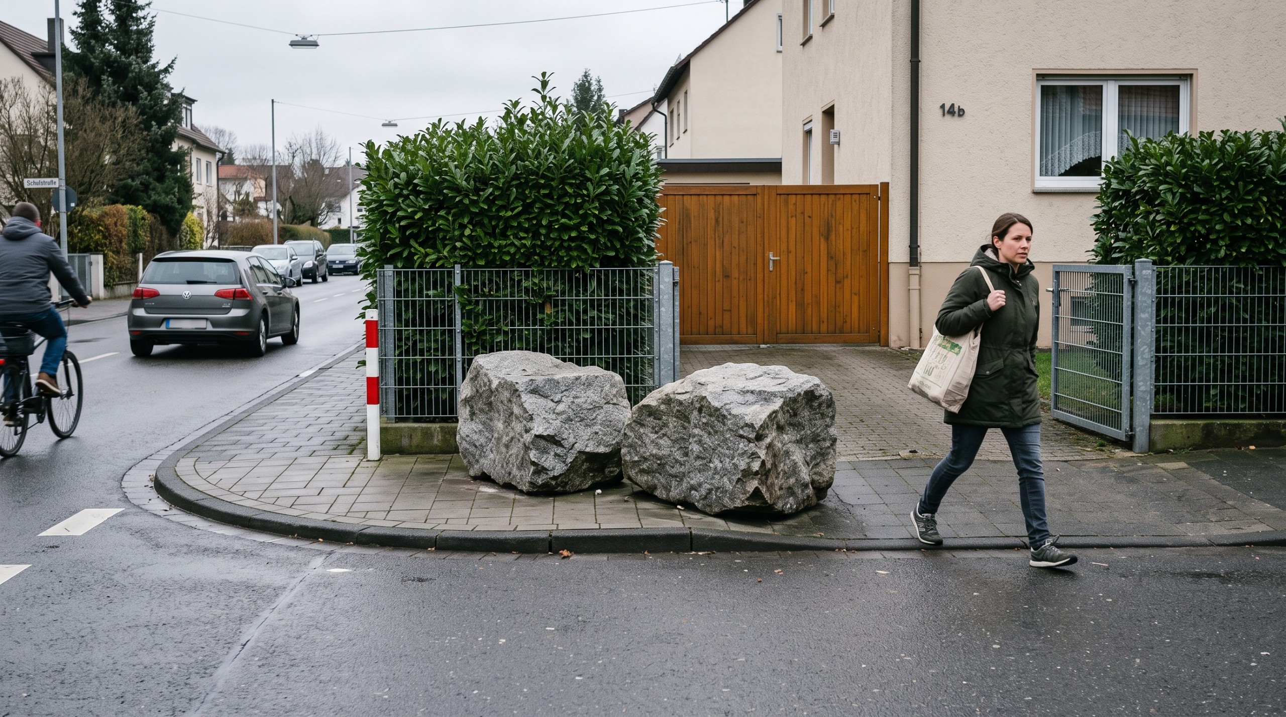 Fußgänger weicht auf engem Gehweg zwei großen Findlingen neben einer Grundstücksausfahrt aus